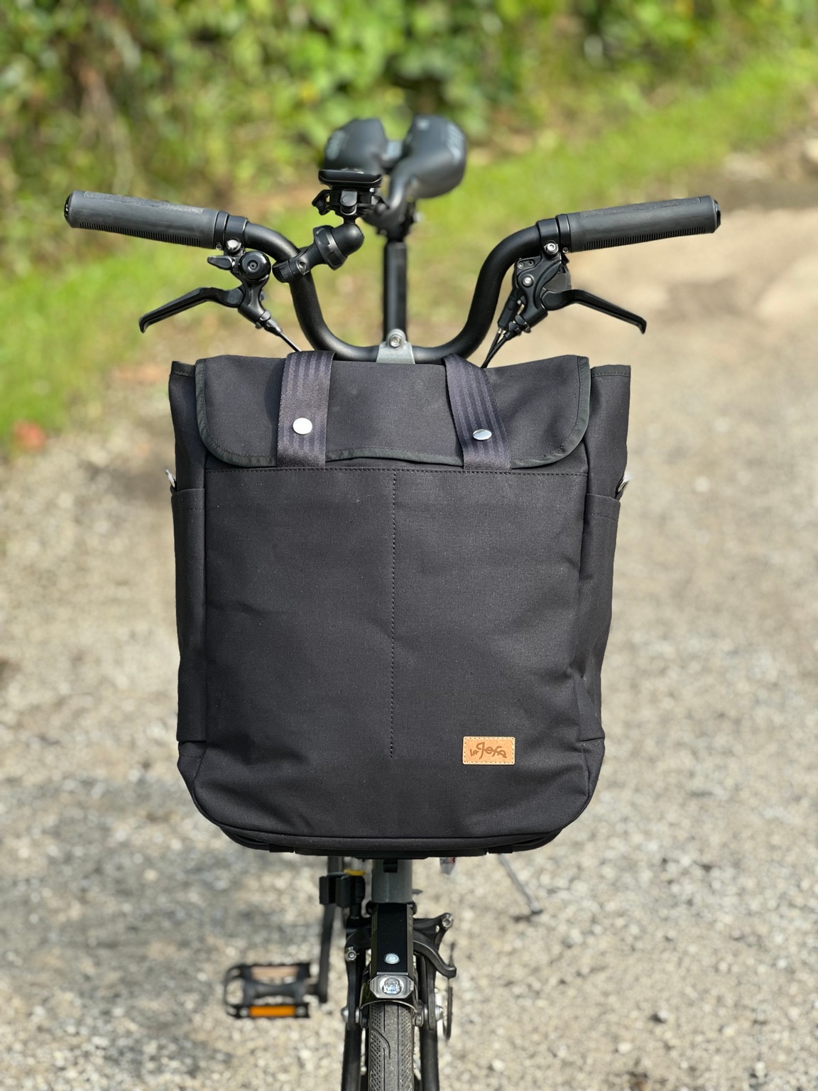 Front view of La Jefa BROBAG Black mounted on a Brompton, with tan brand label and silver snaps