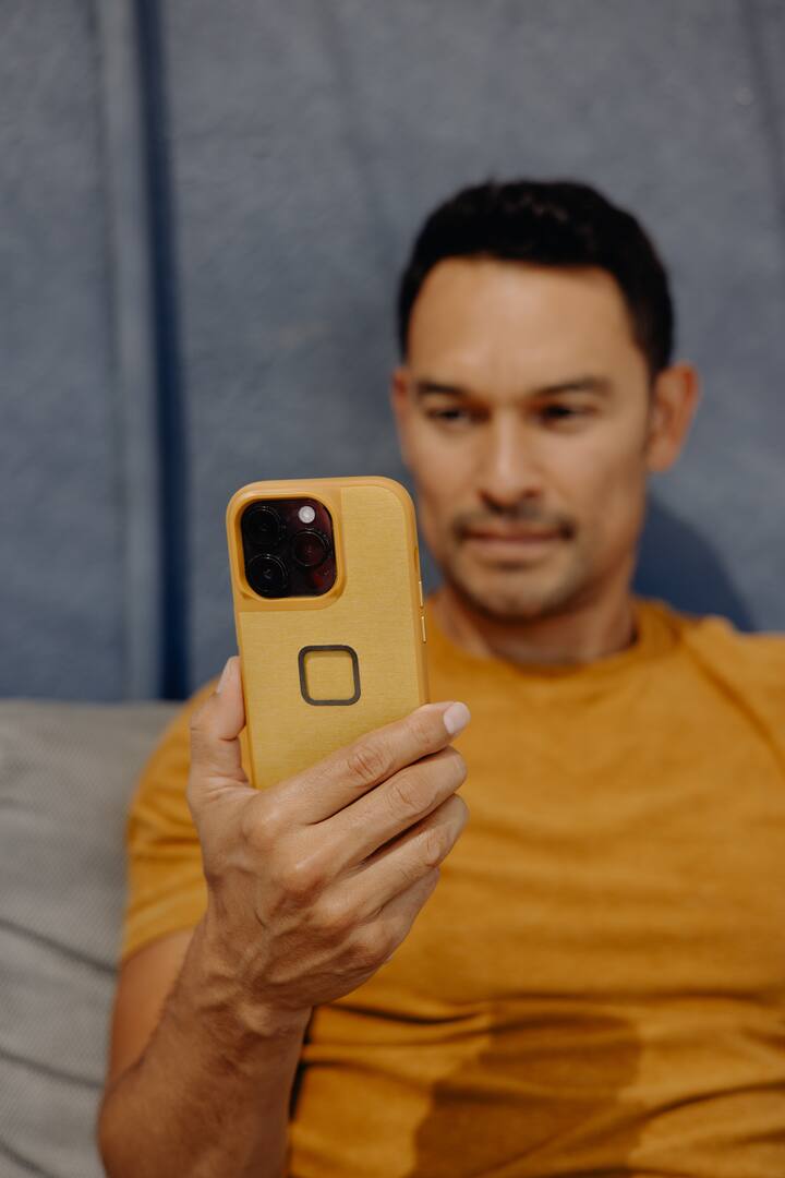 Person holding an iPhone with a Peak Design Sun fabric case and SlimLink mount