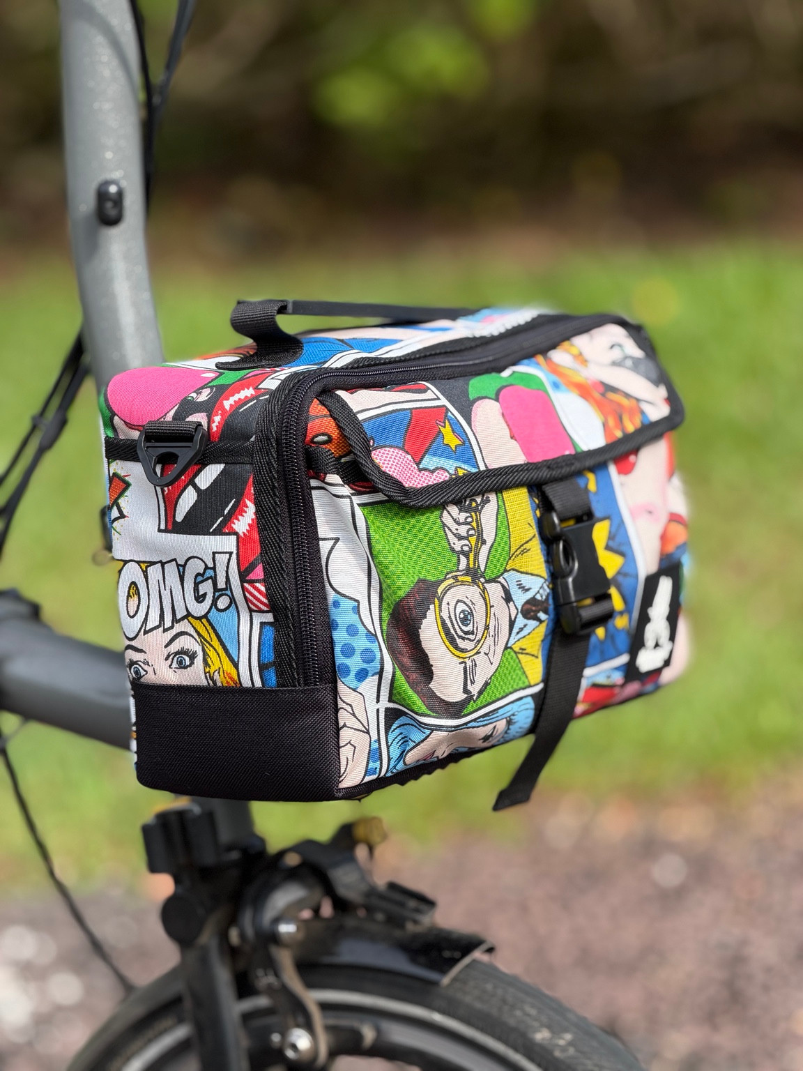Opposite front three-quarter view of Valeria’s Cris Mini #02 with colourful pop-art speech bubbles, black buckle and zipped top